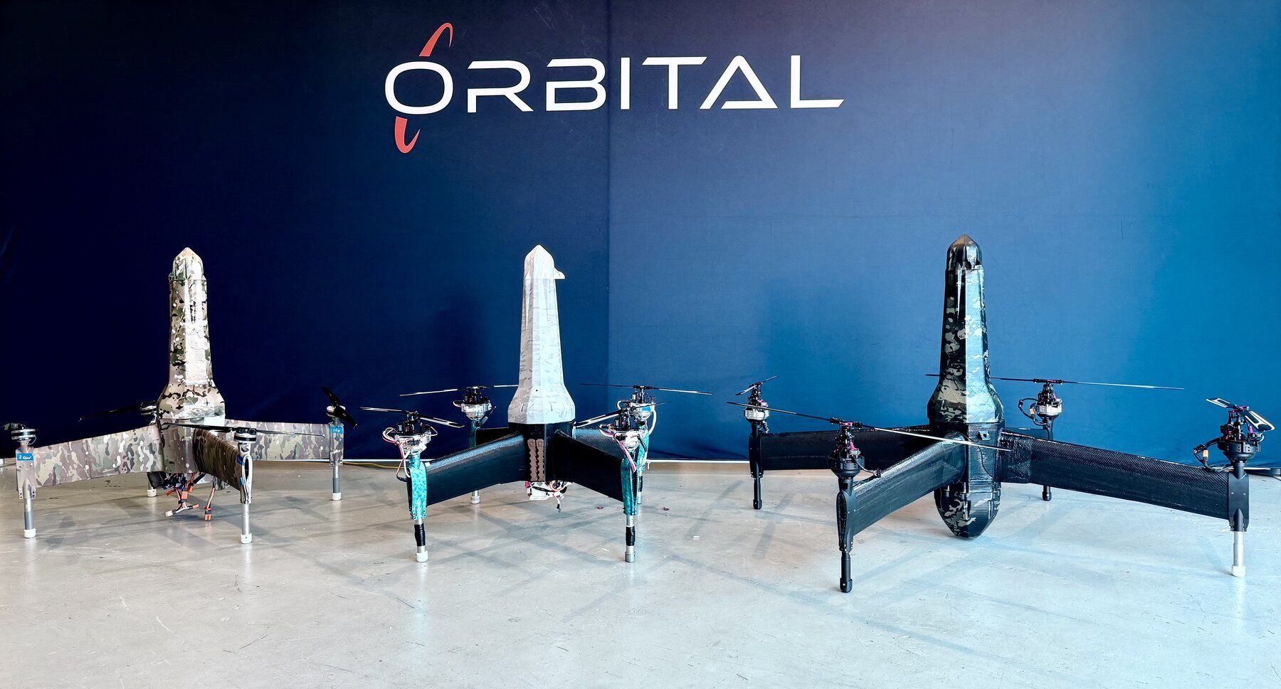 Three Orbital Group 2 composite drone airframes in desert, white, and urban configurations
